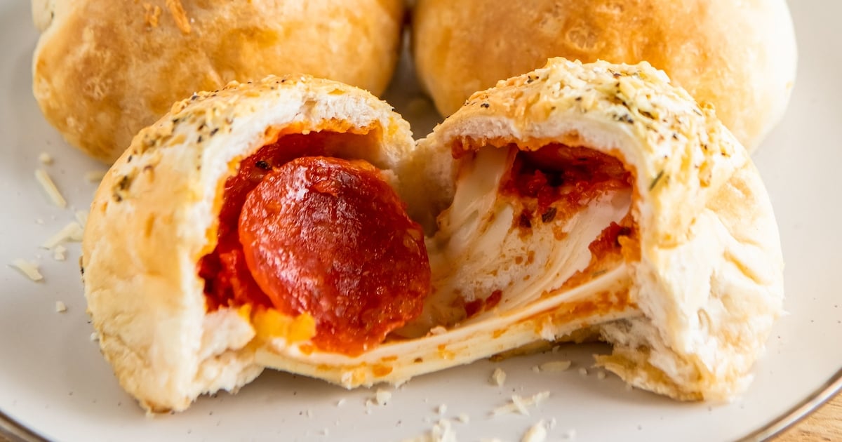 A pepperoni pizza bomb is sliced in half to show melted cheese and pepperoni.