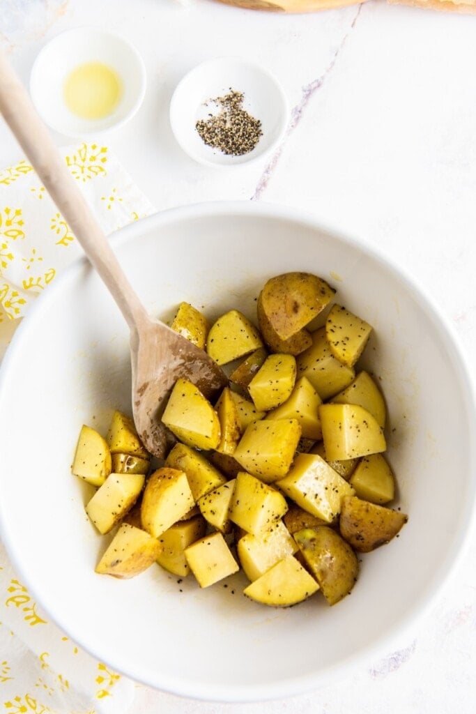 Potato cubes in a bowl with seasoning.