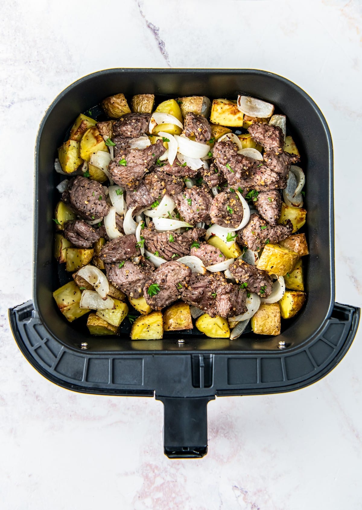 Cooked steak bites, onion, and potatoes in the air fryer.