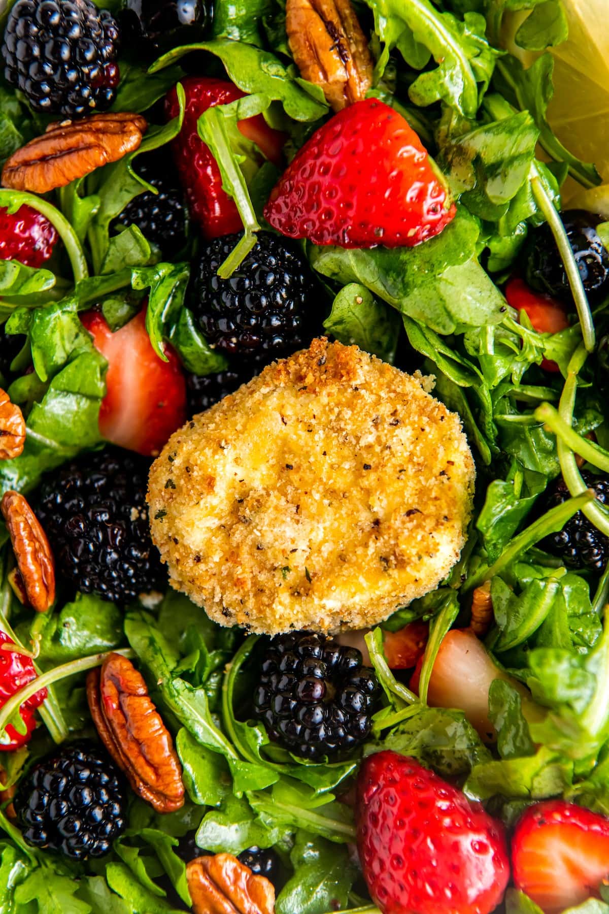 Breaded goat cheese on top of arugula salad with berries.
