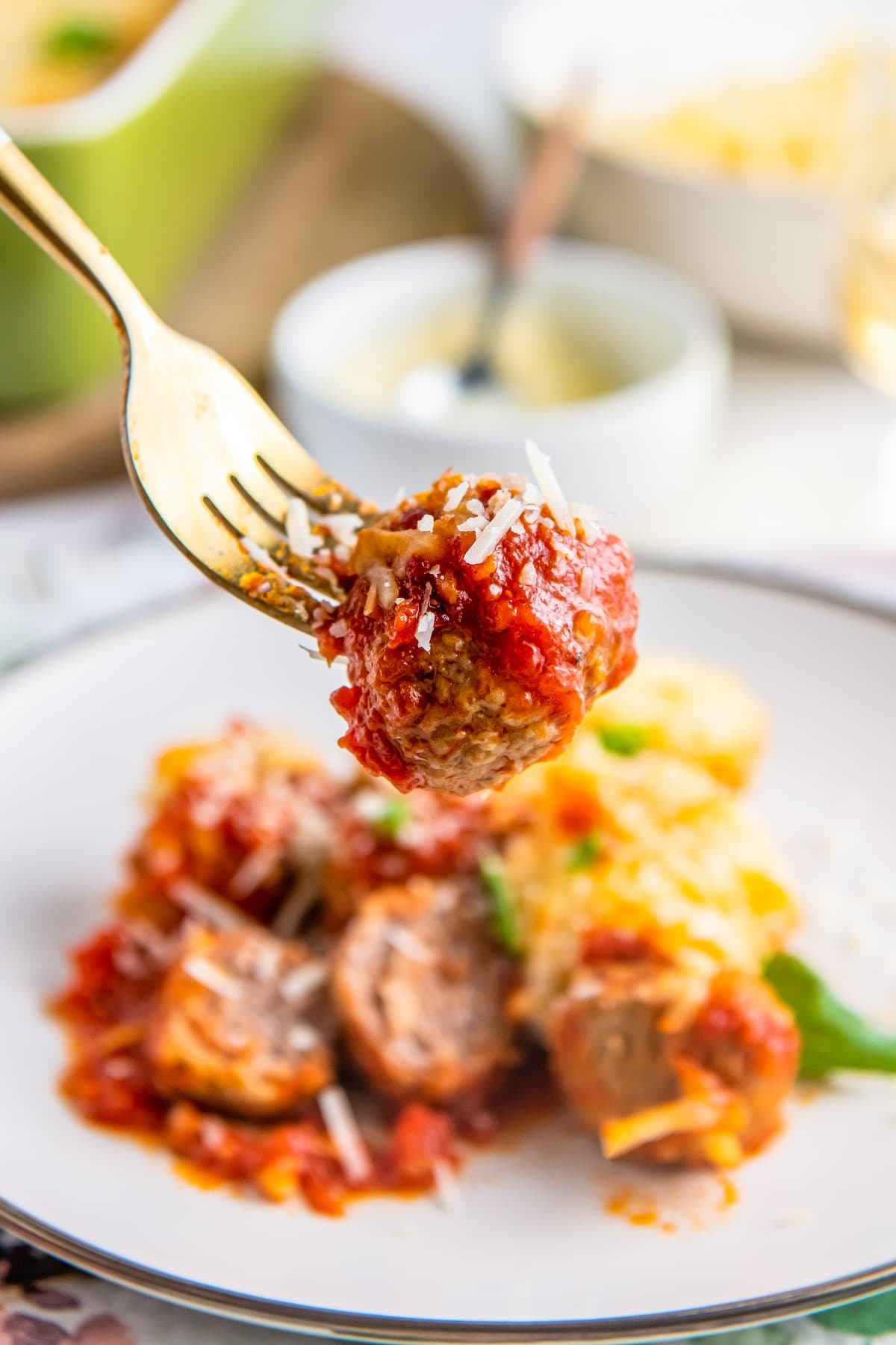 Meatball covered in marinara on a fork.