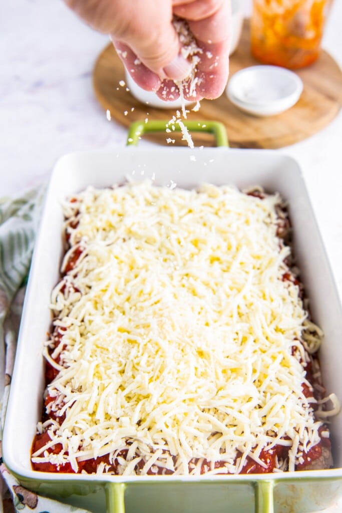 A layer of parmesan and mozzarella cheese over marinara covered meatballs.