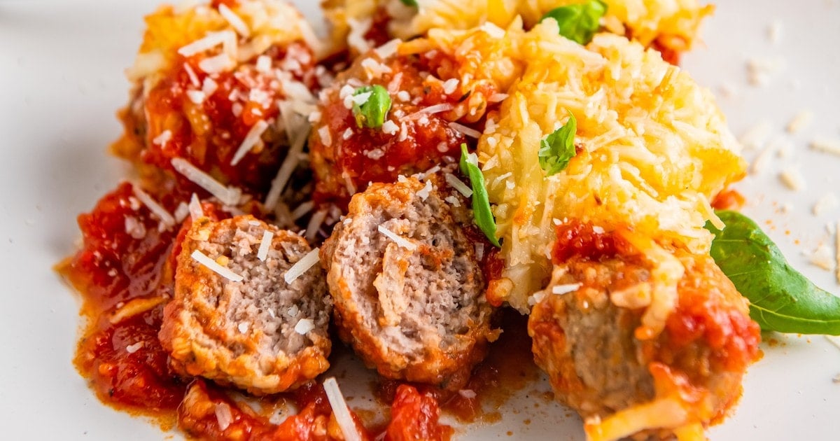 Baked meatballs in marinara on a plate.