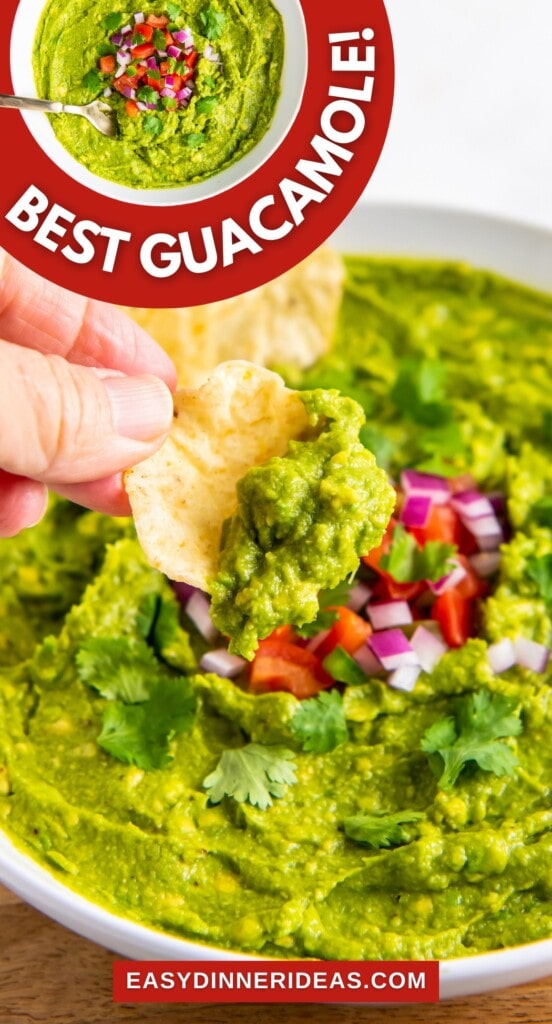 A bowl of guacamole with pico de gallo on top and a tortilla chip scooping up a bite.