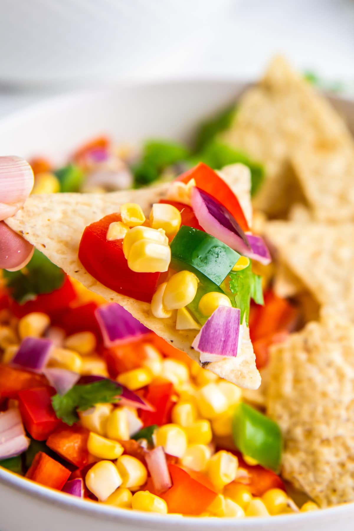 Corn salsa on a tortilla chip with jalapeno pepper.