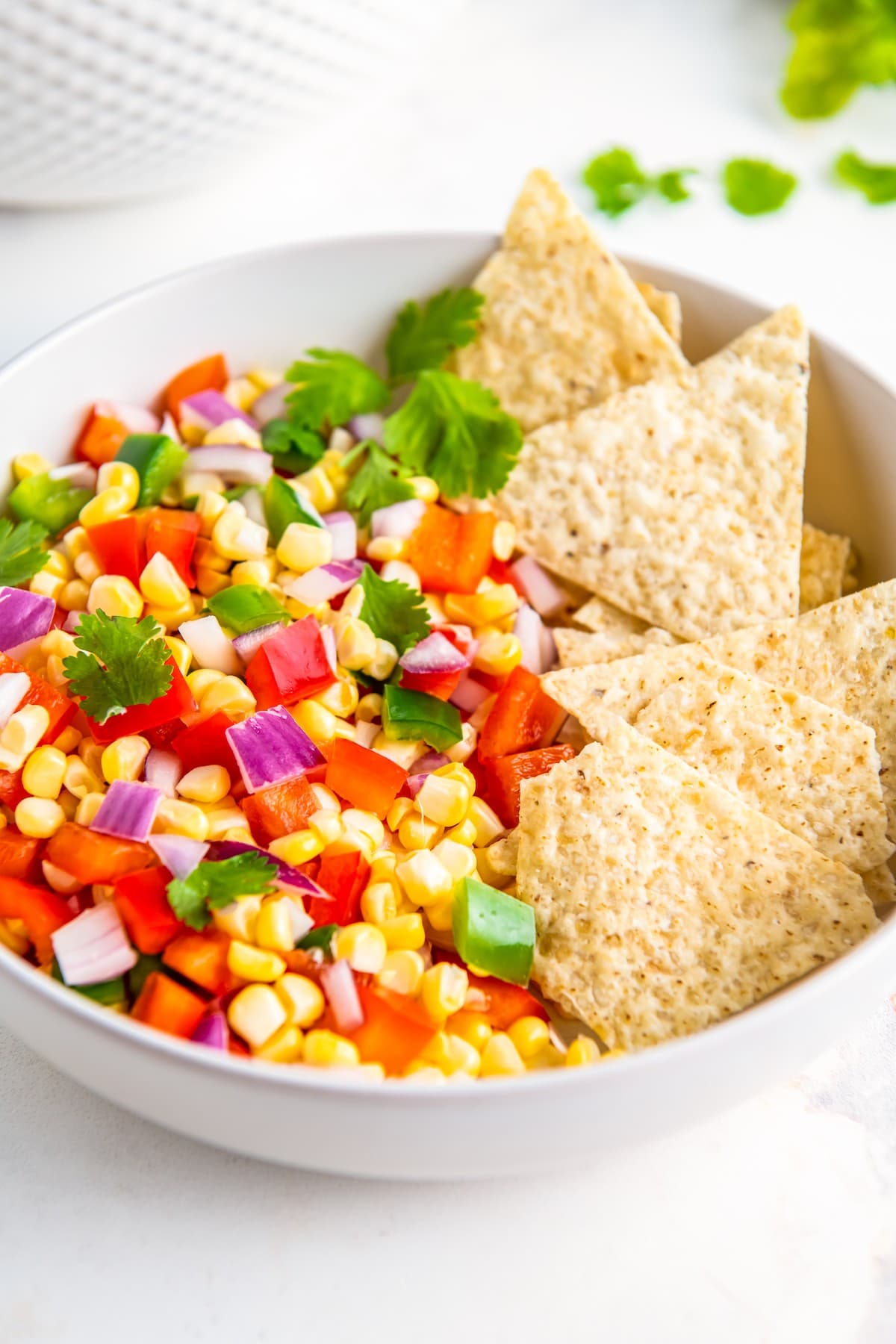 Tortilla chips in a bowl with corn salsa.