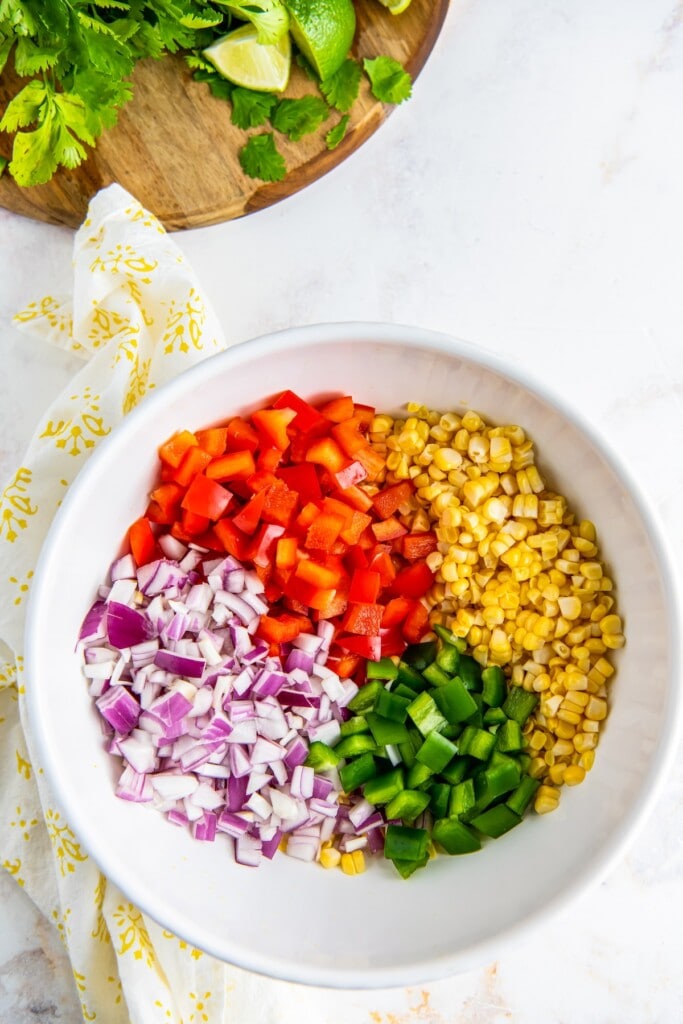 Corn, red onion, bell pepper, and jalapeno in a bowl.