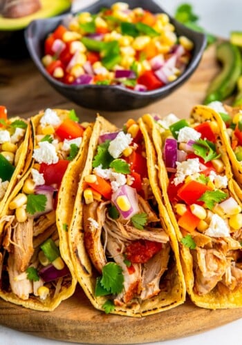 Chicken tacos topped with corn salsa and cheese.