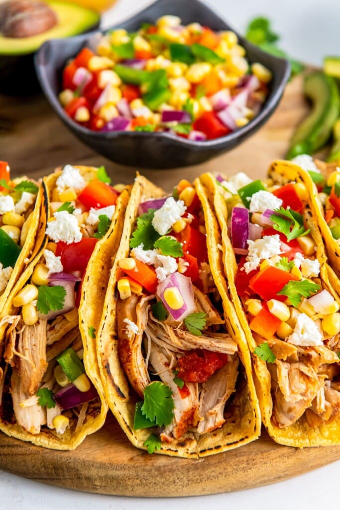 Chicken tacos topped with corn salsa and cheese.