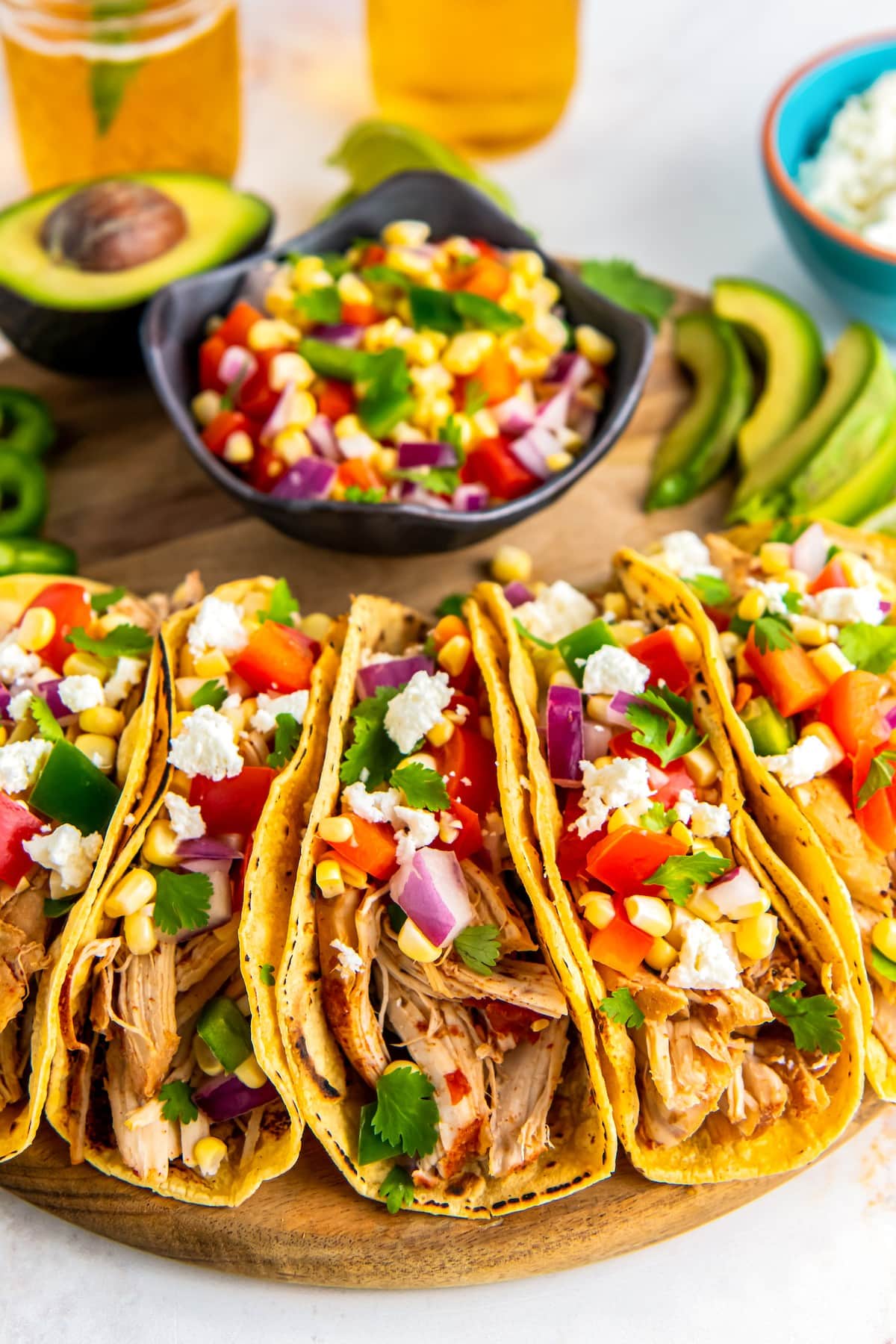 Slow cooker chicken tacos topped with crumbled cheese and corn.