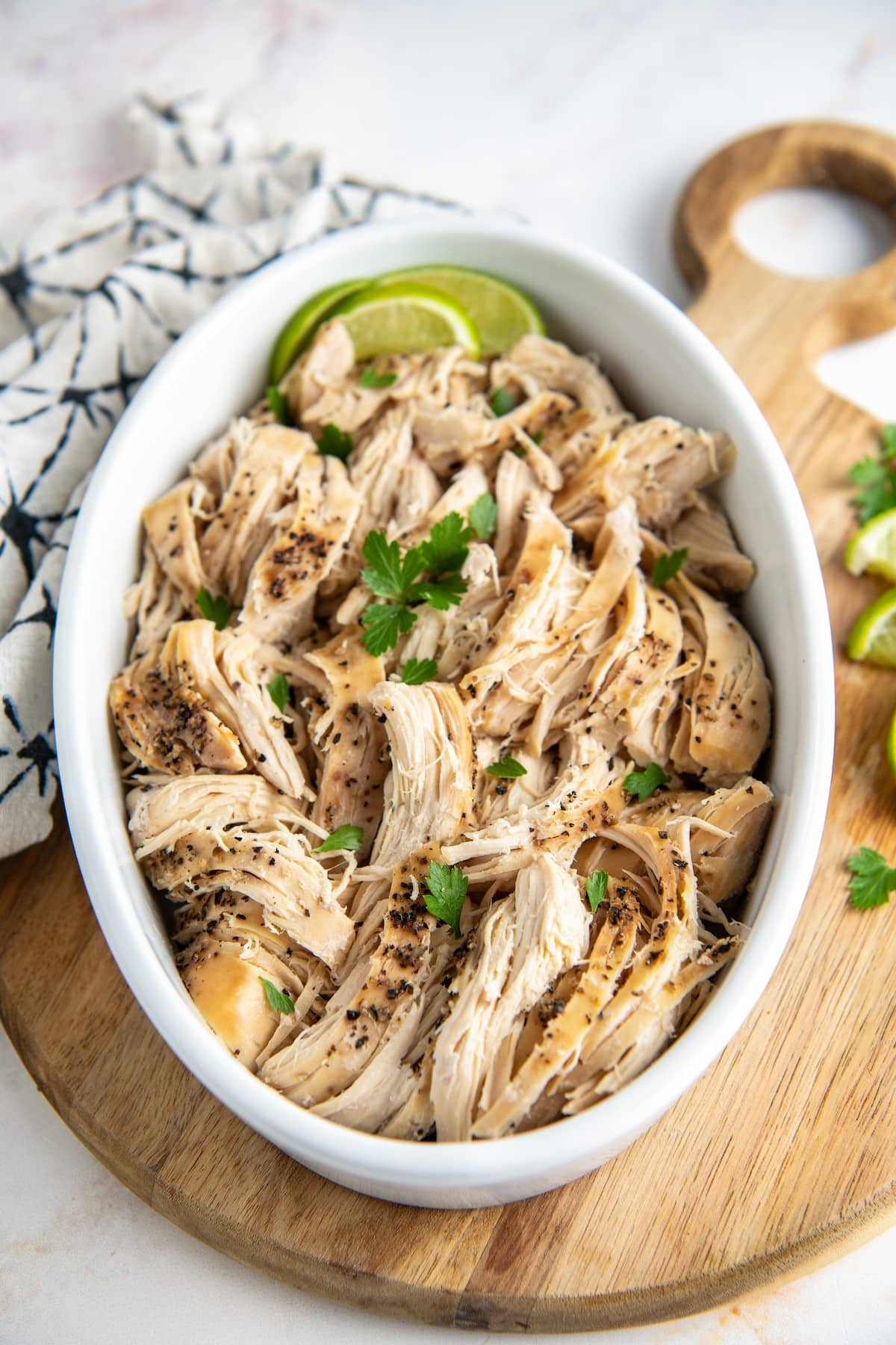 Pulled chicken with lime wedges in a crockpot.