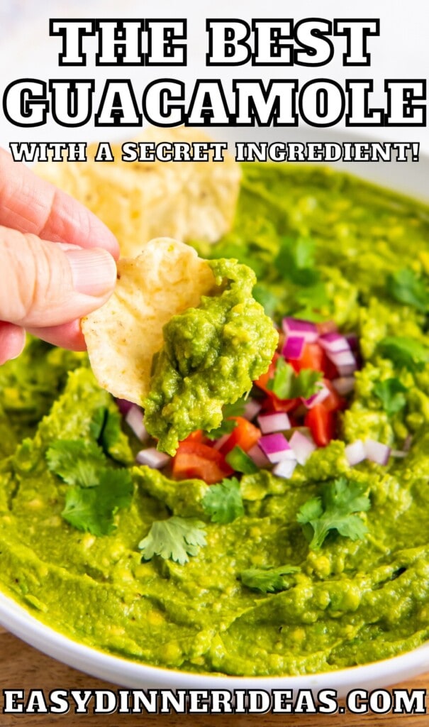 A bowl of homemade guacamole with tortilla chips scooping up a bite.