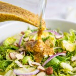 Honey mustard salad dressing poured over a brussels sprouts salad.