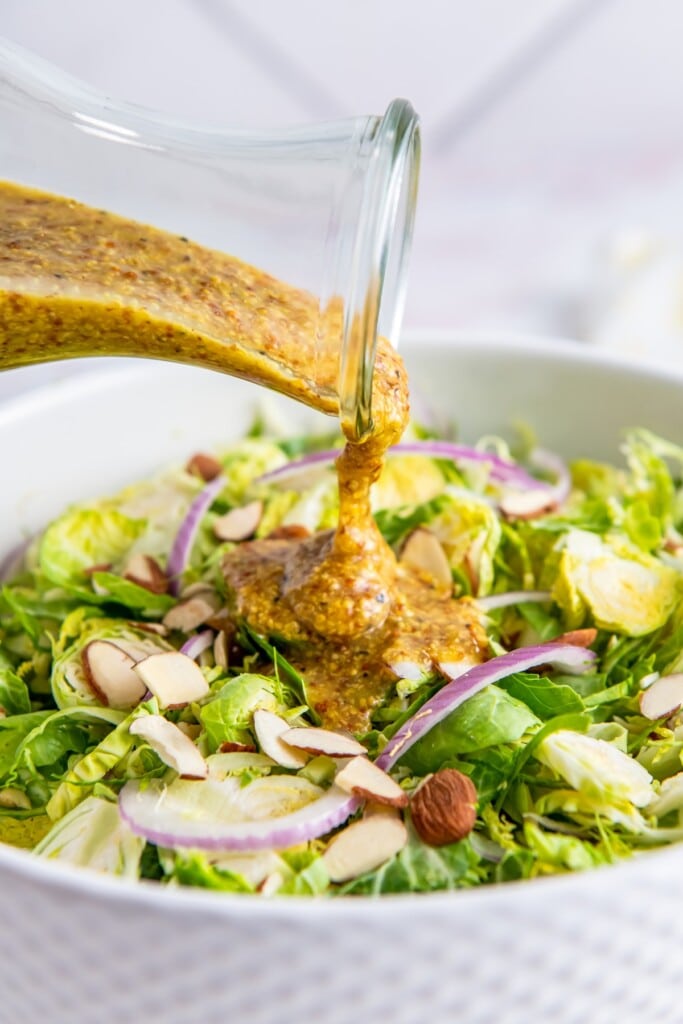Honey mustard salad dressing poured over a brussels sprouts salad.