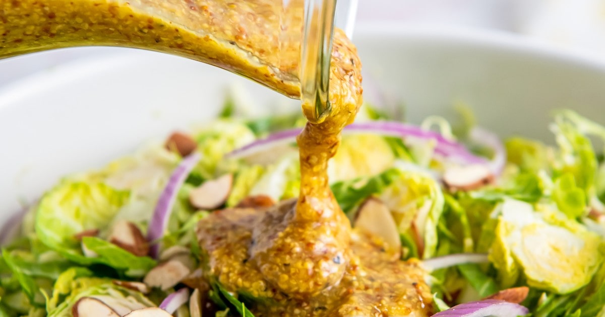 Homemade dijon mustard dressing poured over a brussels sprouts salad.