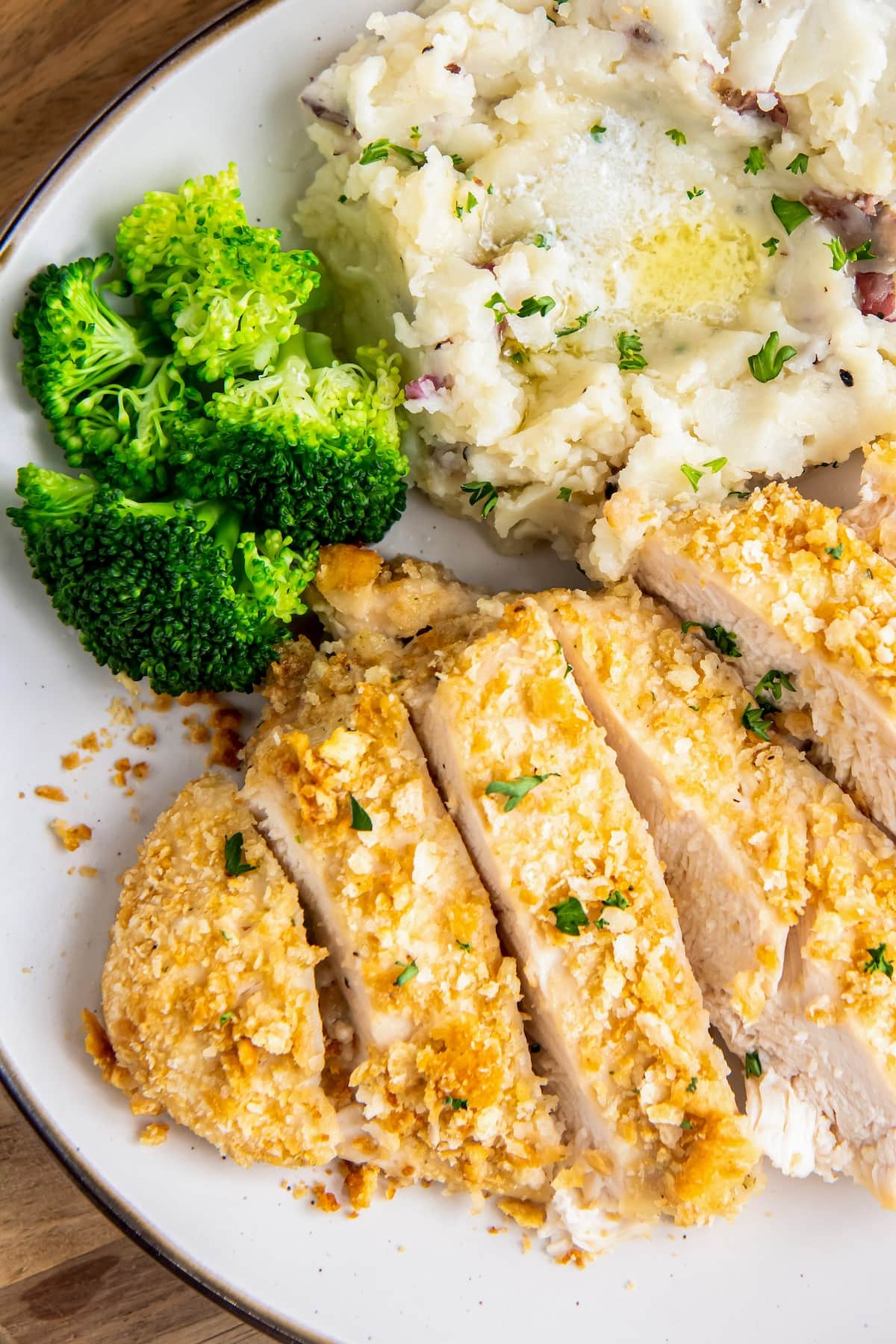 Crispy chicken breast with broccoli and mashed potatoes on a plate.