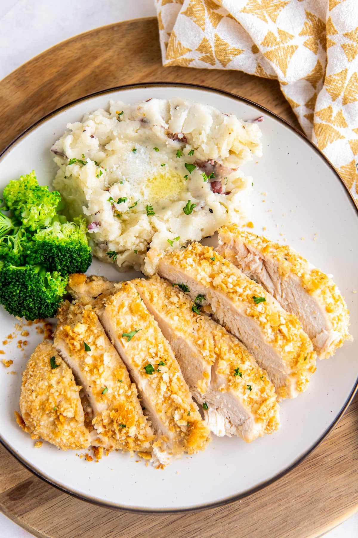 Sliced ritz chicken with veggies and mashed potatoes.