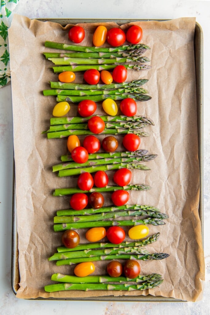 Fresh asparagus and cherry tomatoes on a tray.