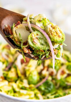 Brussels sprouts with red onion slices on a serving spoon.