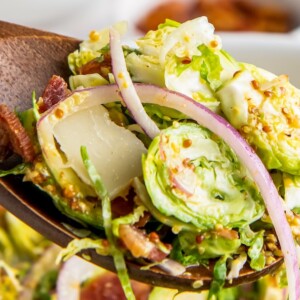 Shredded brussels sprouts salad with onion and bacon bits.