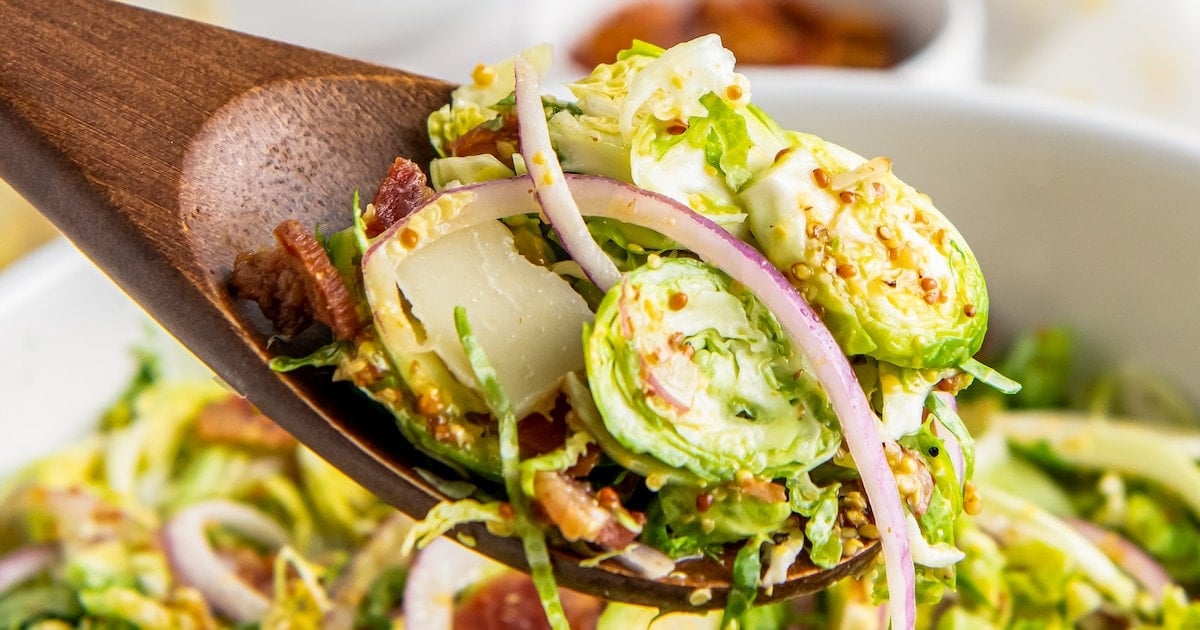 Shredded brussels sprouts salad with onion and bacon bits.