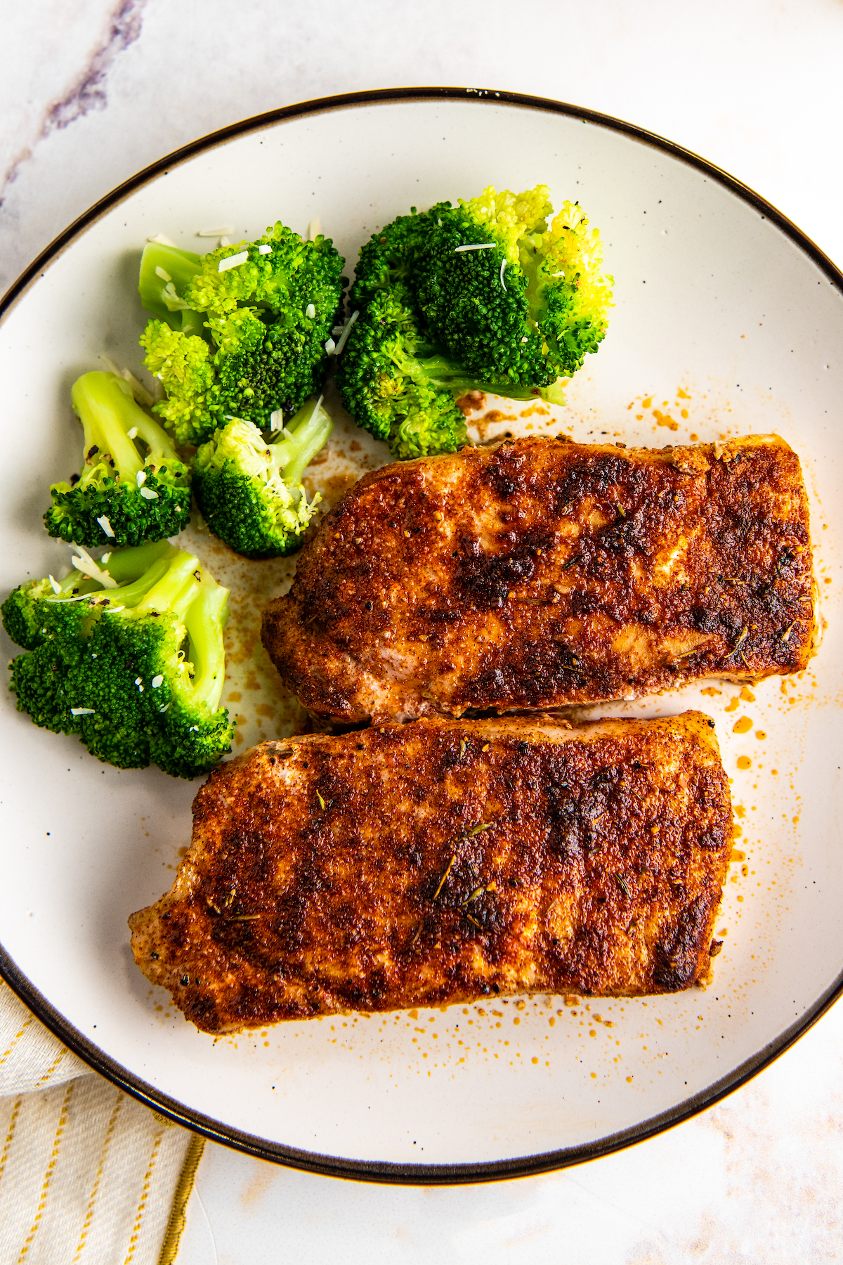 Pork chops on a plate with steamed broccoli.