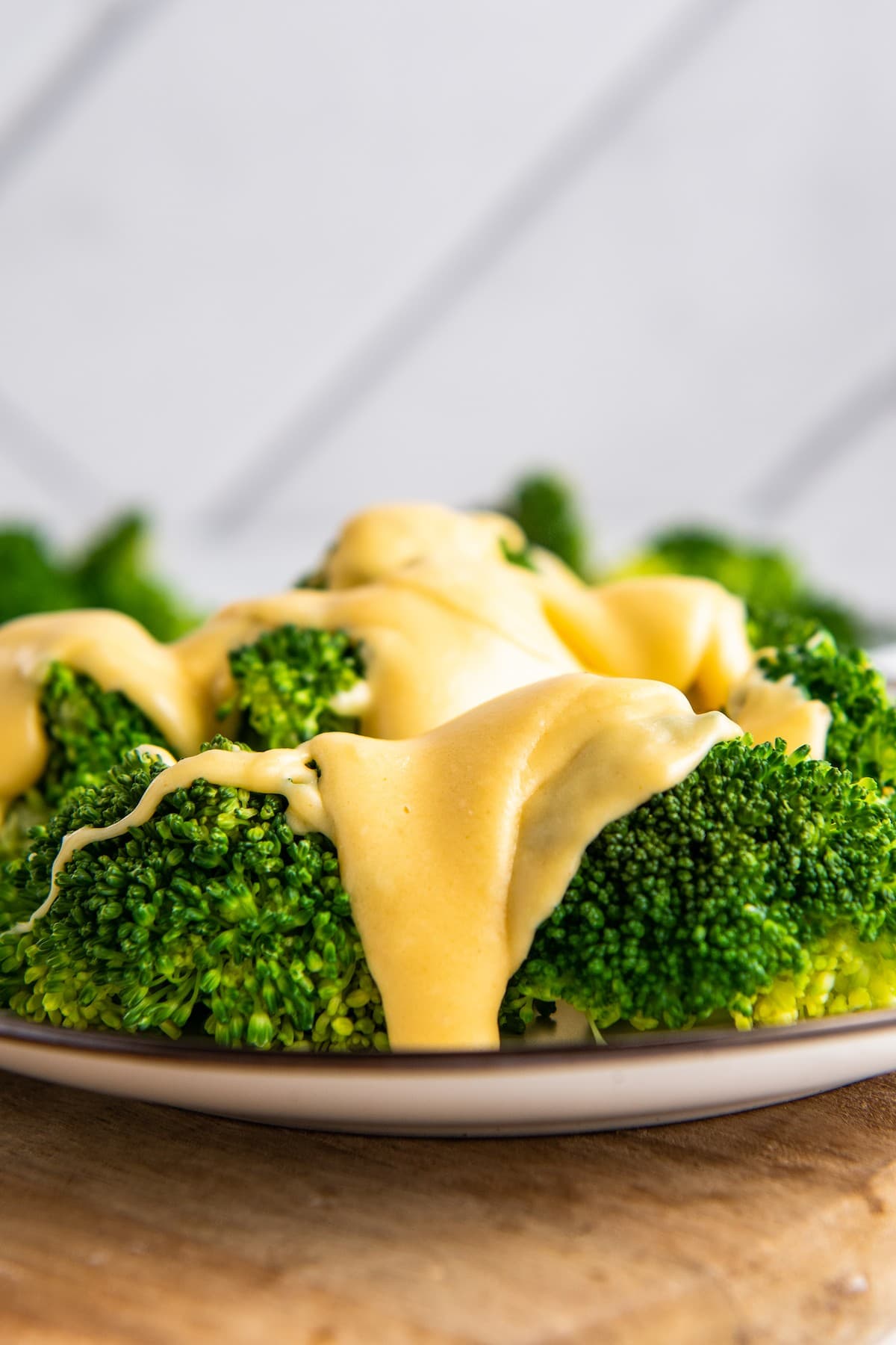 Cheddar cheese sauce poured over a plate of broccoli.