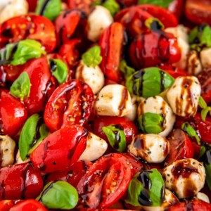 A bowl of Cherry Tomato Caprese Salad with a drizzle of balsamic glaze on top.