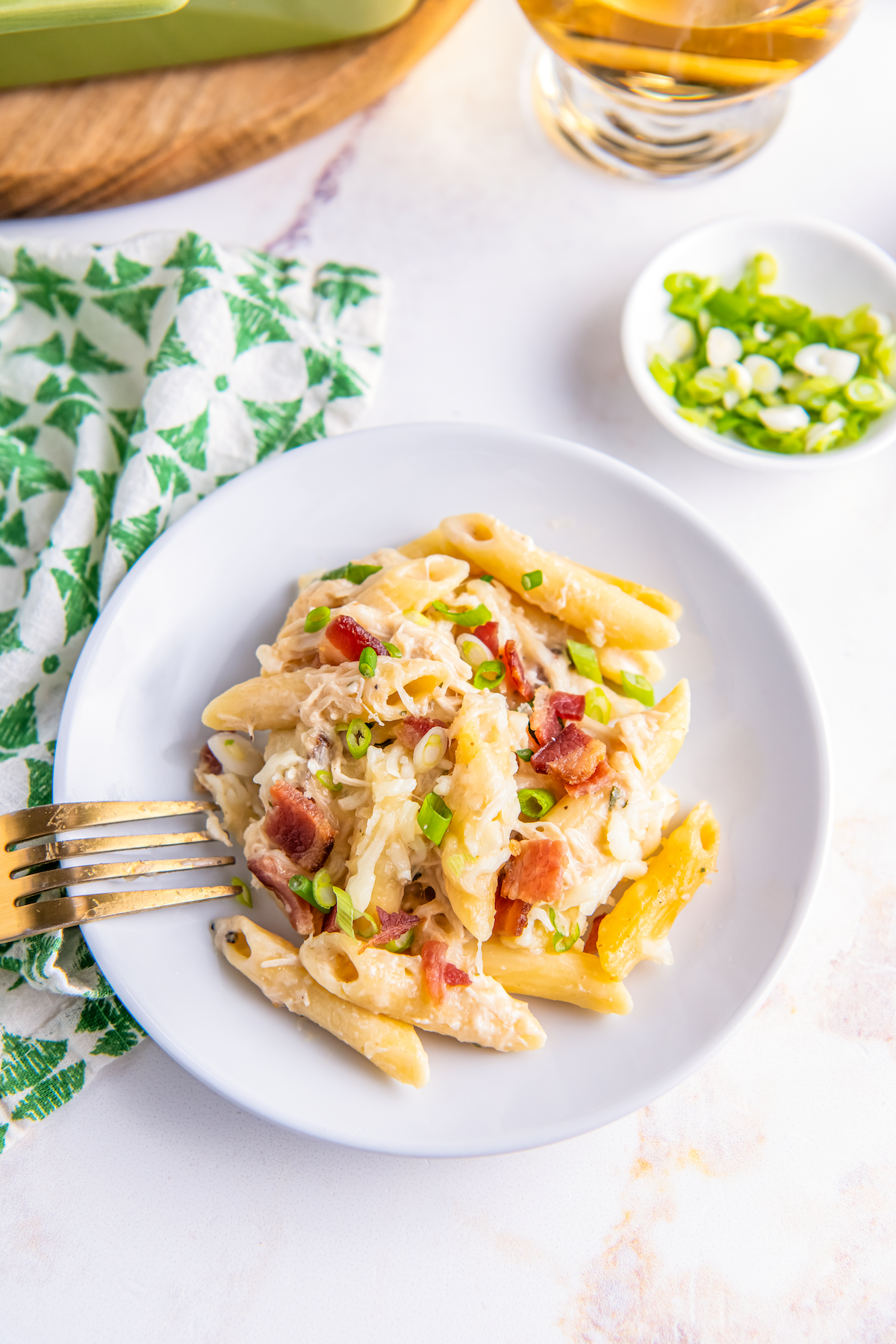 Plate of cheesy chicken pasta with bacon bits.