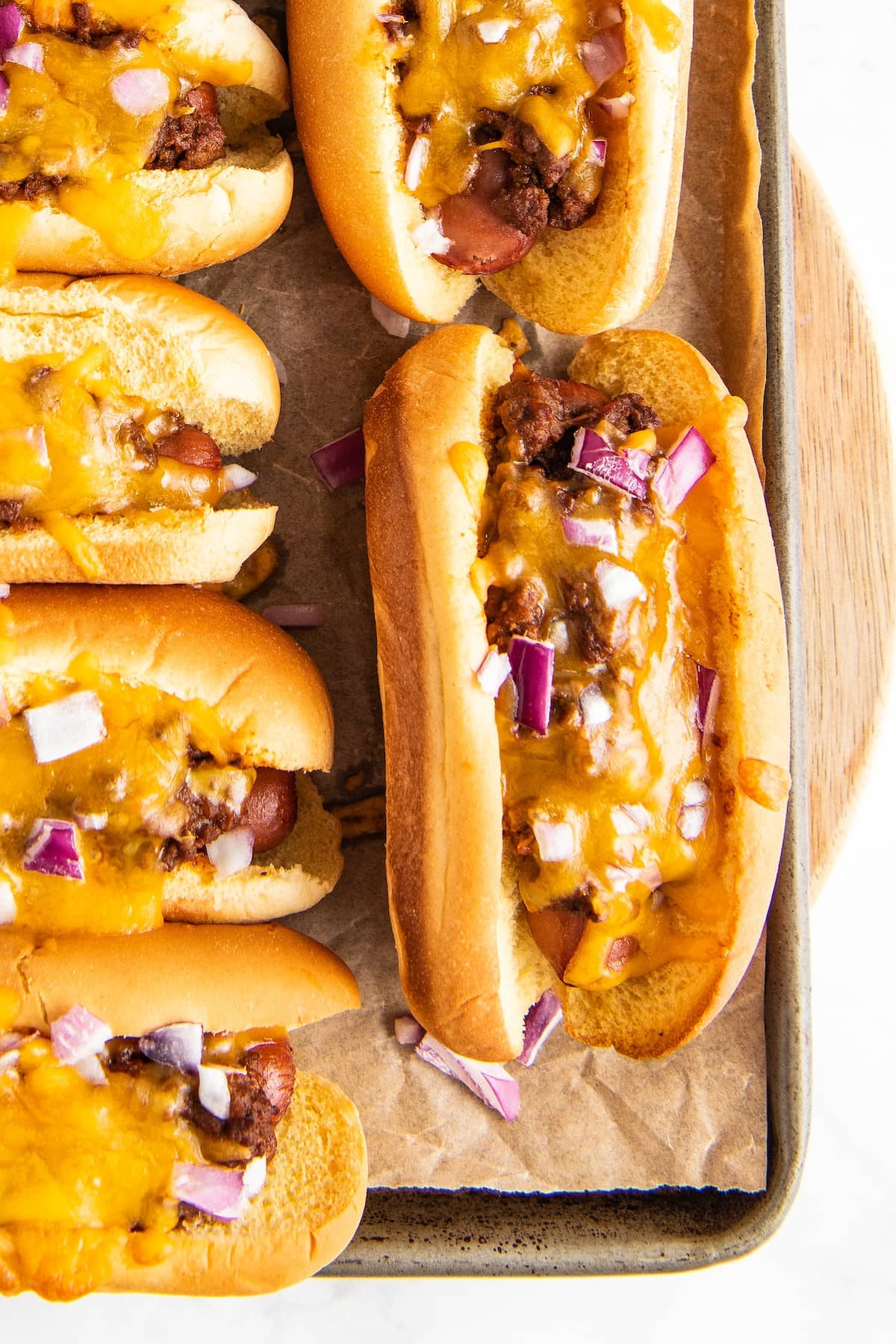 Chili hot dogs with melted cheddar cheese and chopped red onion.