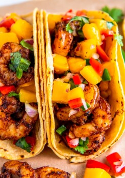 Two air fryer shrimp tacos with corn tortillas and fresh mango salsa on top.