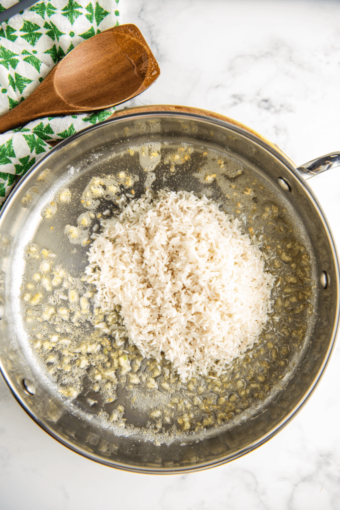Rice cooking in a skillet with garlic.