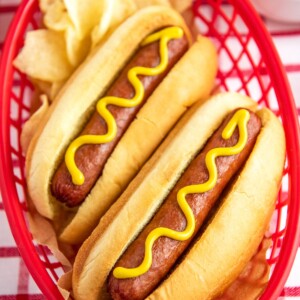 Hot dogs in buns with a squirt of mustard.