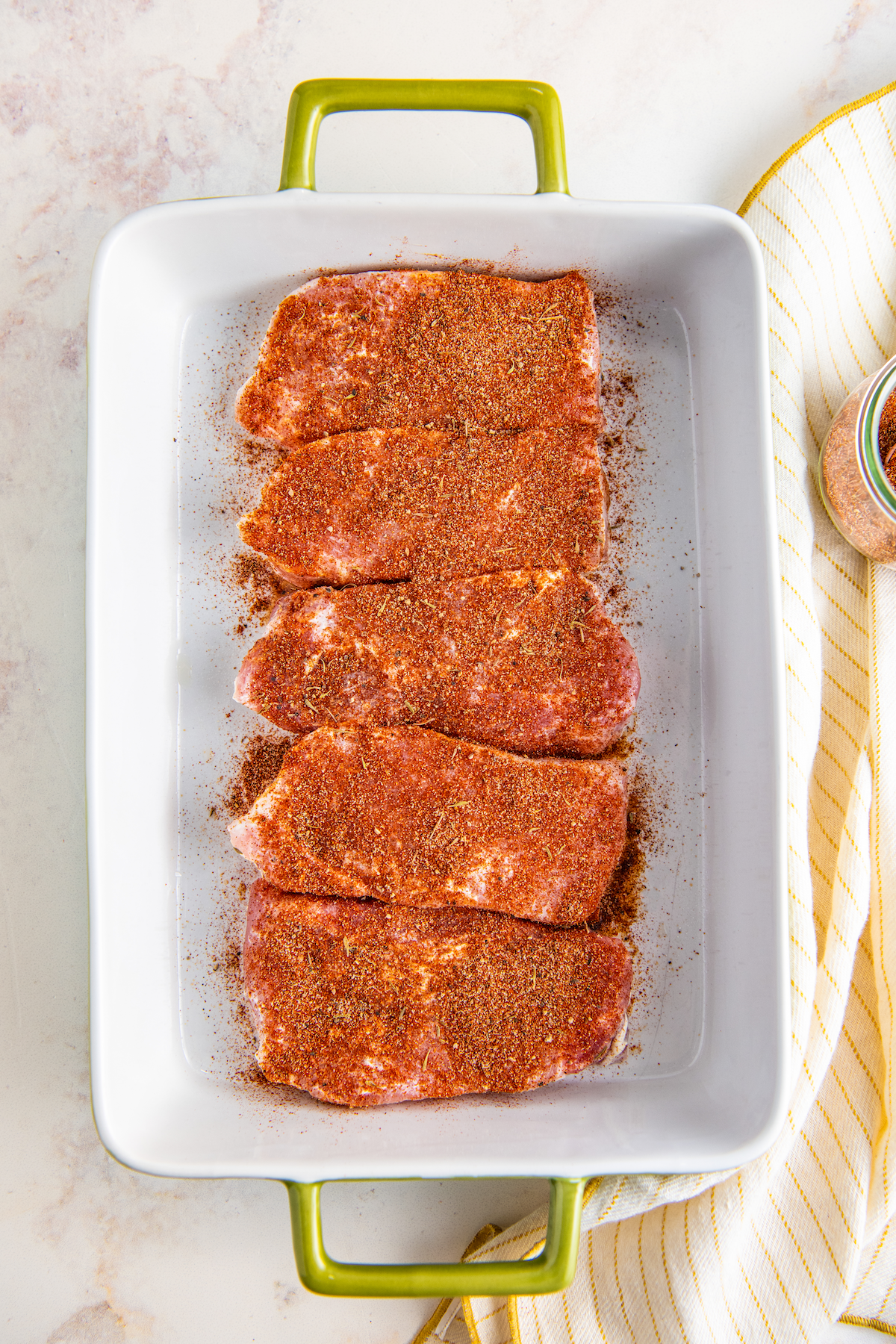 Pork chops in a baking dish covered with pork seasoning.