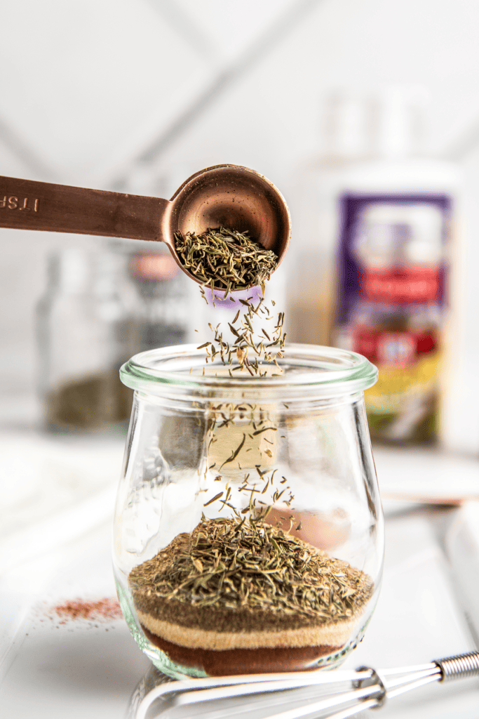 Dried thyme poured into a glass jar.