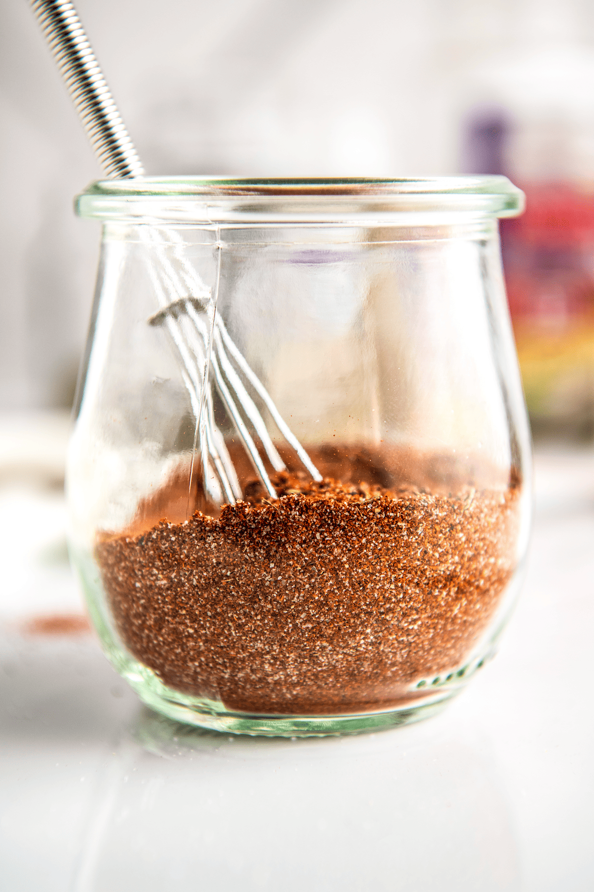 Mixed seasonings and spices in a glass jar.