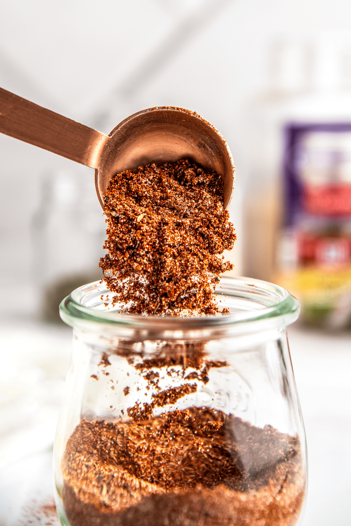 Tablespoon of pork seasoning poured into a jar.