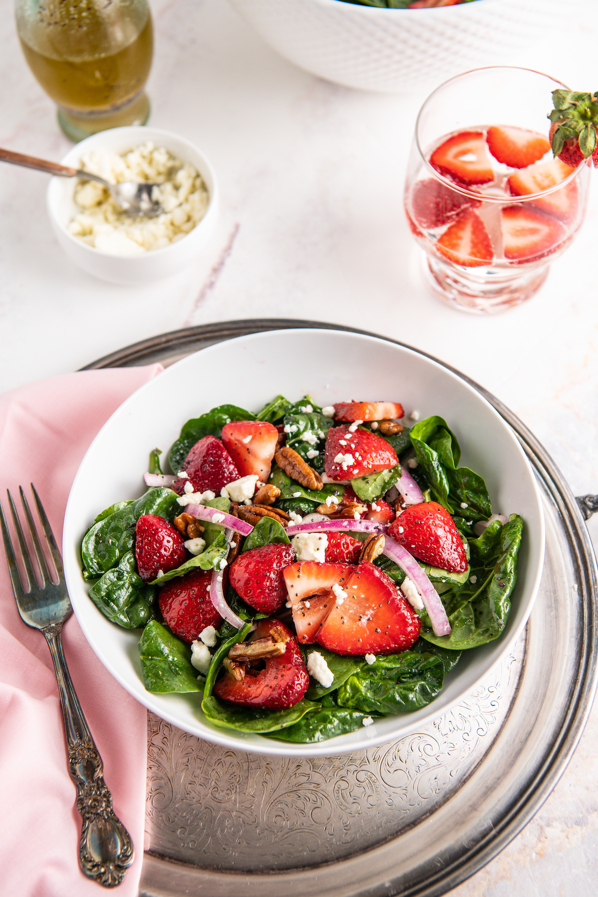 Bowl of spinach strawberry salad topped with feta cheese.