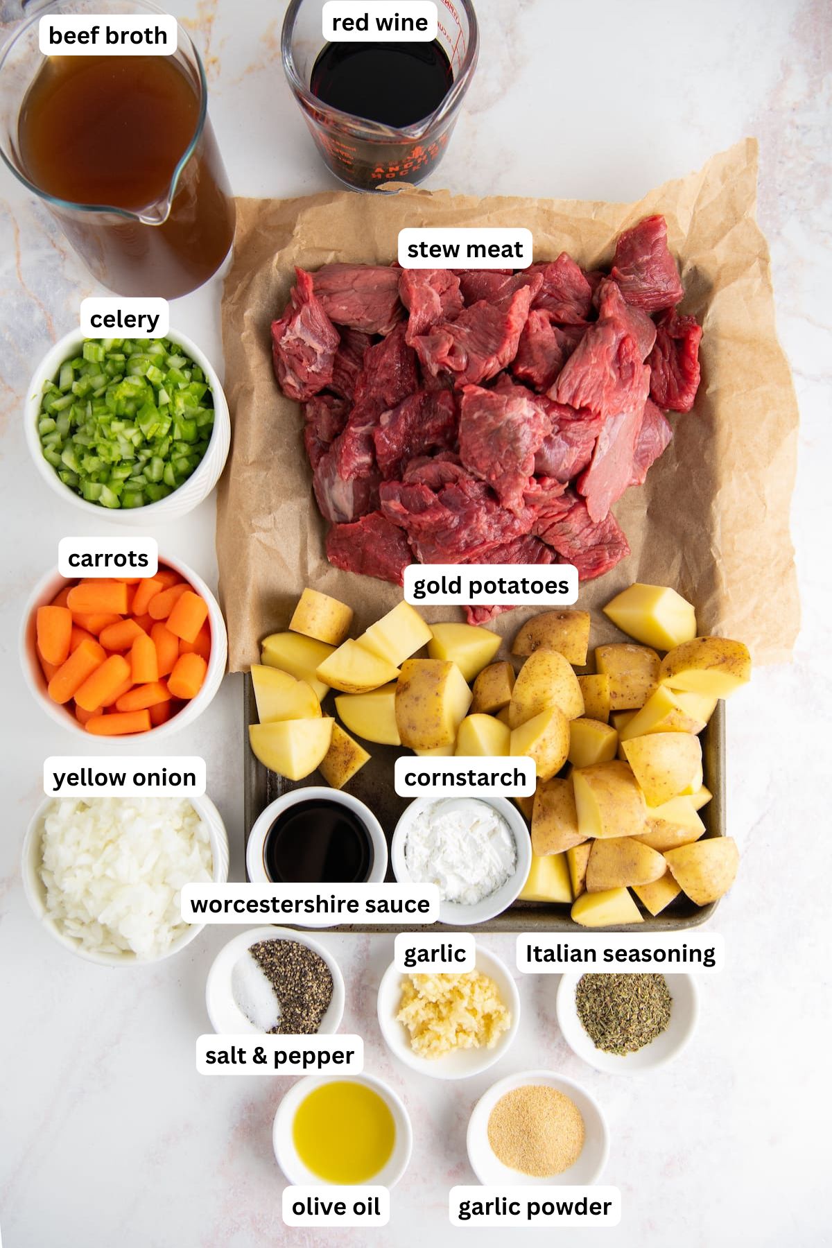 The ingredients for instant pot beef stew recipe in order from top to bottom: beef broth, red wine, celery, carrots, onions, stew beef, gold potatoes, worcestershire sauce, cornstarch, salt and pepper, garlic, italian seasoning, olive oil, garlic powder.