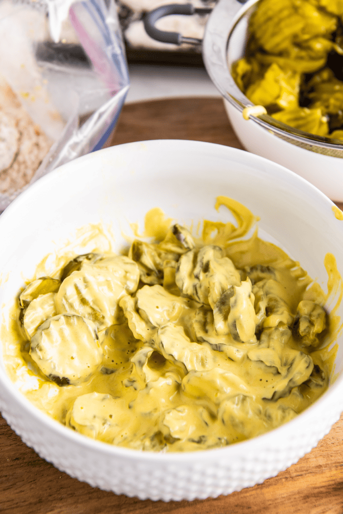 A bowl of pickle slices in mustard and mayo