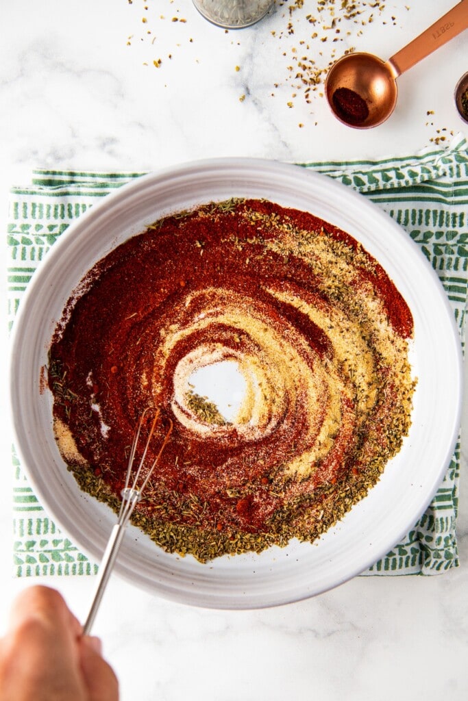 A whisk mixing together the ingredients for blackened seasoning in a bowl