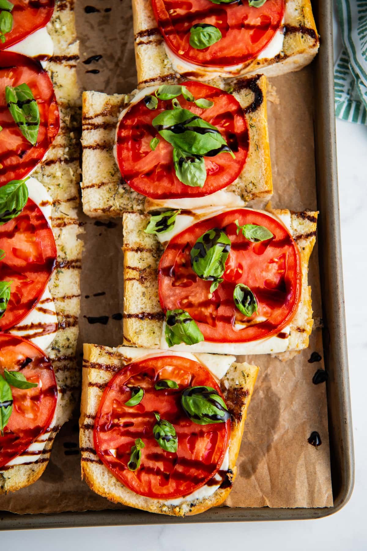 Two loaves of Caprese sandwiches on a baking sheet, cut into slices
