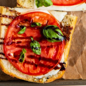 Close up of a slice of Caprese sandwich topped with basil and balsamic
