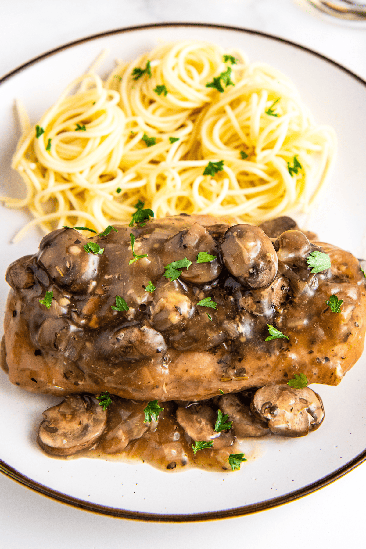 A plate with chicken marsala and spaghetti on it