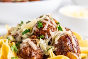A plate of pasta and meatballs, with another plate in the background