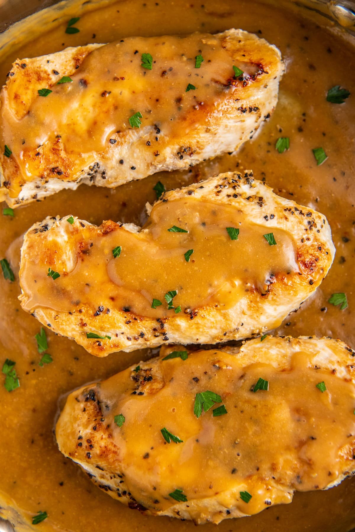 Overhead view of three chicken breasts covered in gravy