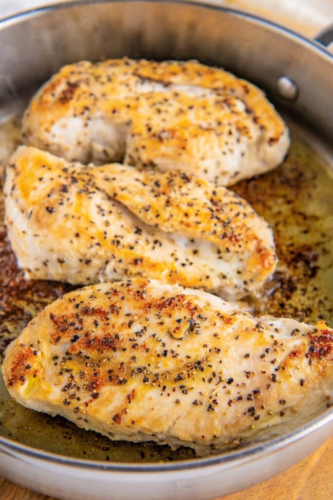 Three seasoned and cooked chicken breasts in a pan