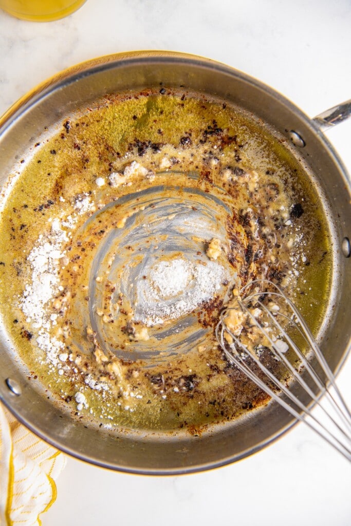 Overhead view of a whisk whisking a roux in a skillet