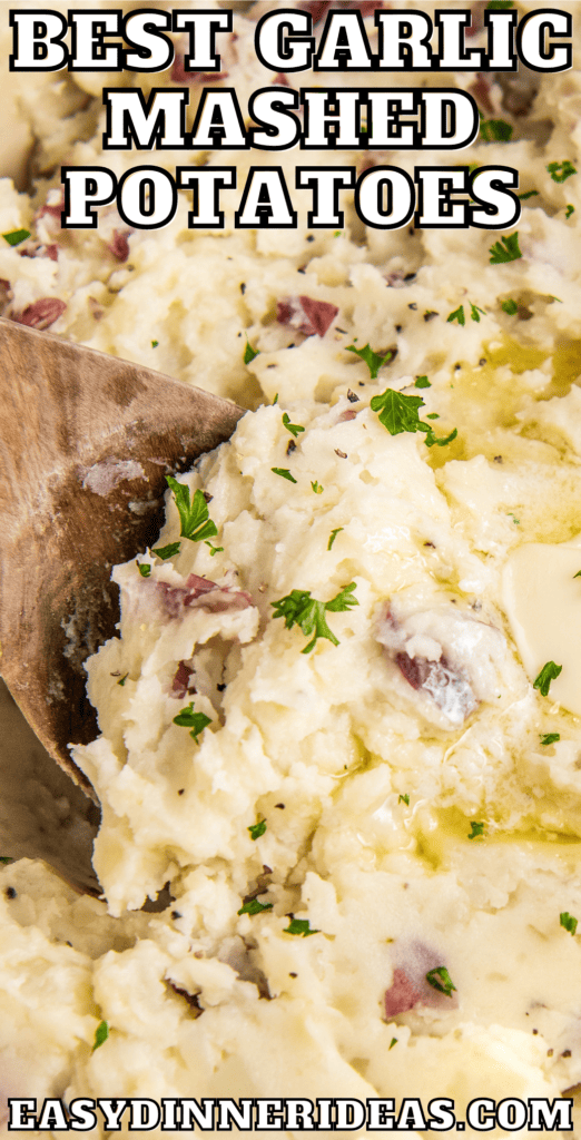 Garlic mashed potatoes in a pot with a wooden spoon scooping them up.