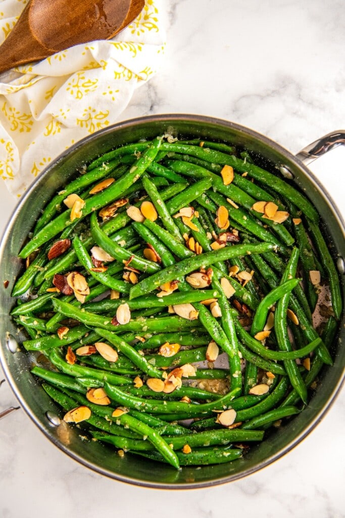 Overhead view of green beans topped with almonds in a skillet